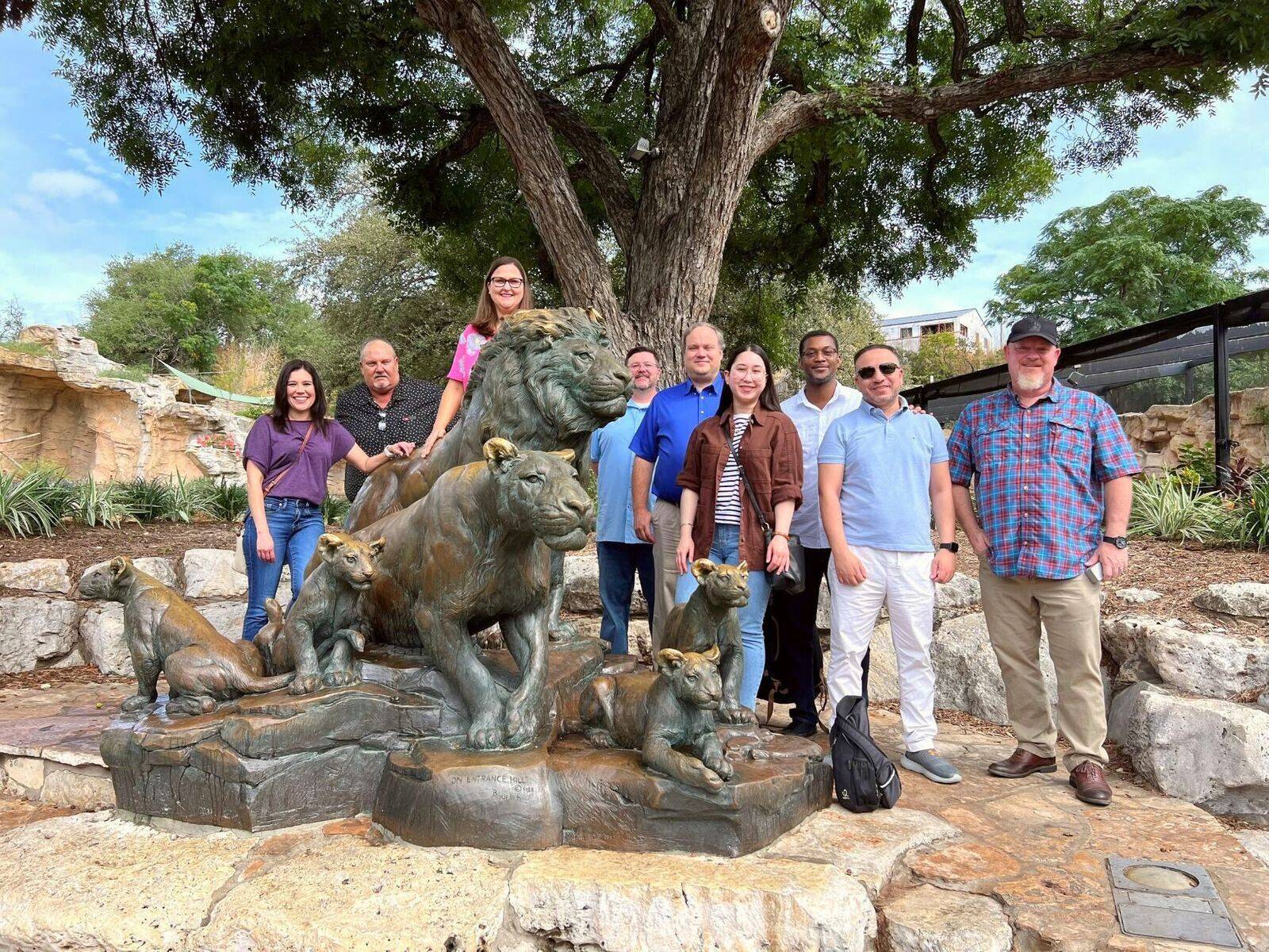 Sunland team members posing around a lion sculpture